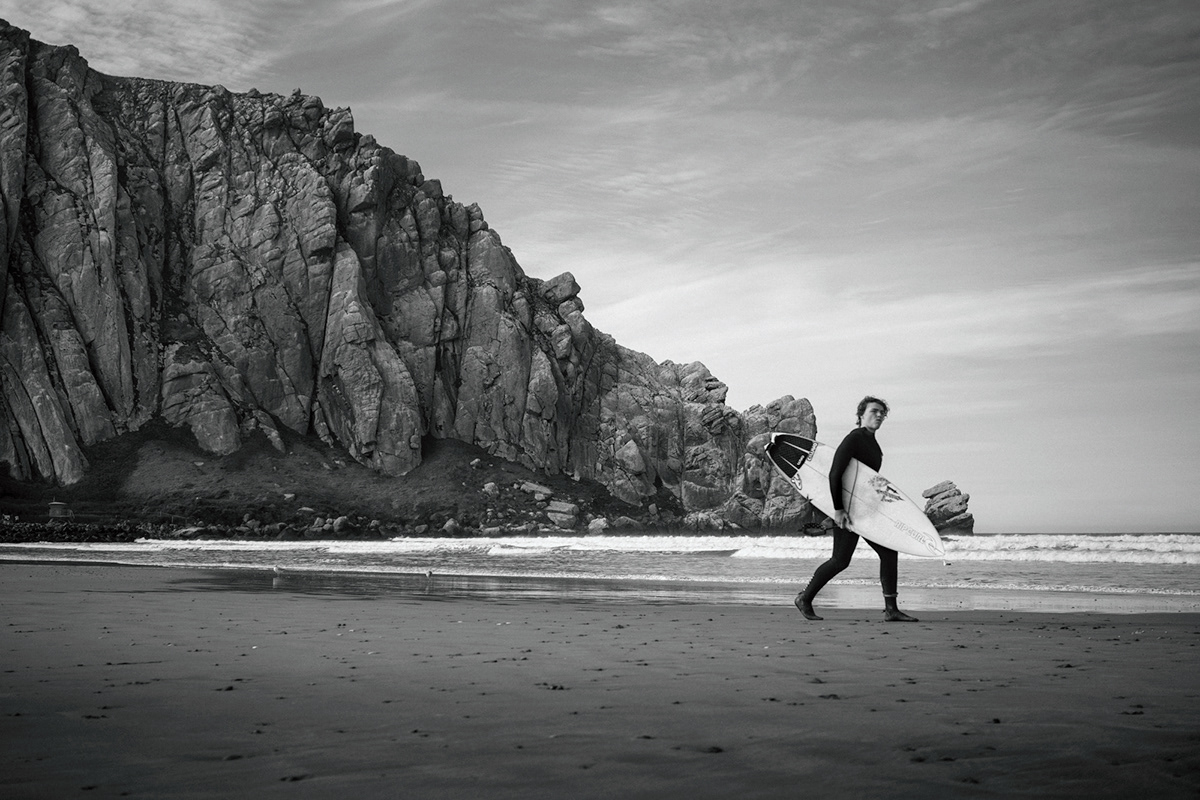Surfer walking along the beach below Morro Rock